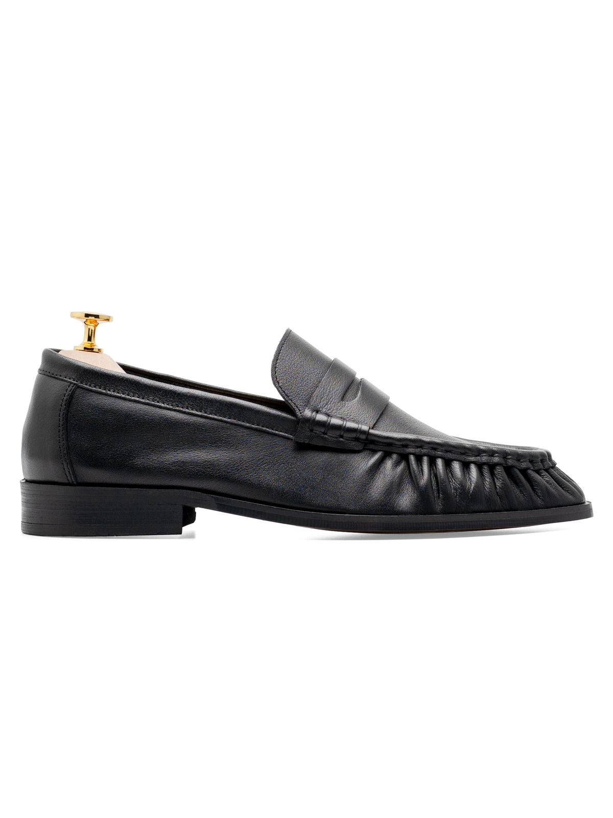 Black leather loafer with penny strap and ruched toe, displayed on gold shoe tree