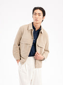 Men's beige corduroy jacket with navy shirt and white trousers, stylish casual wear