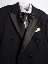 Black tuxedo with satin lapels, bow tie, and gold pocket square, paired with white dress shirt for formal events.