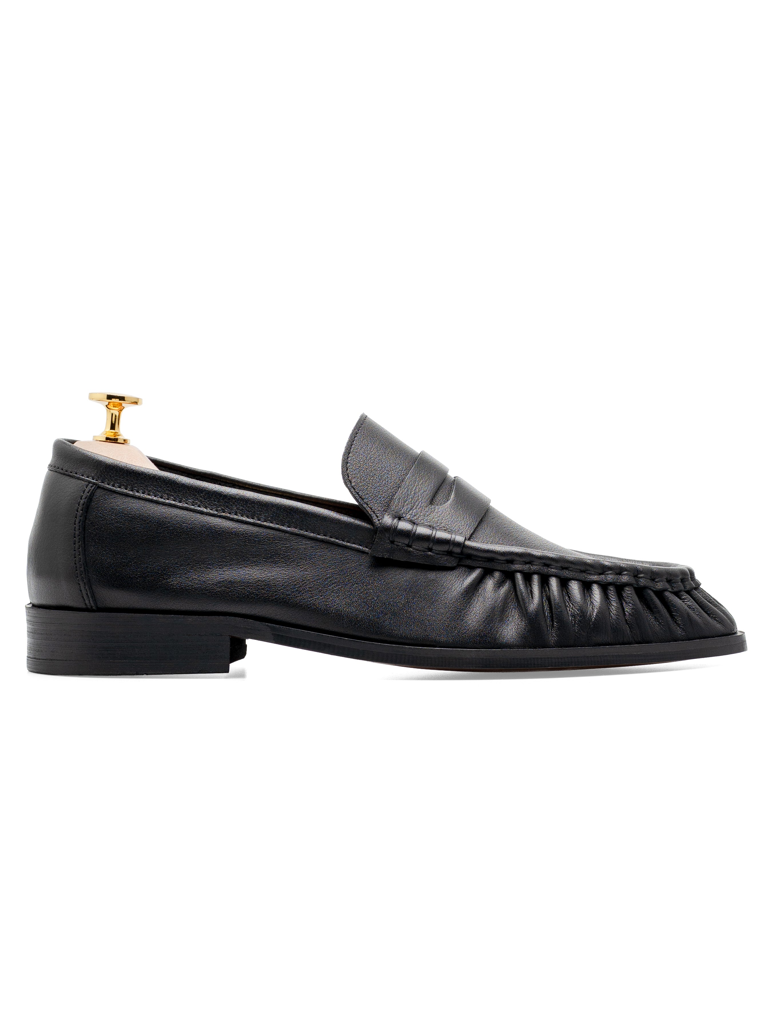 Black leather loafer with penny strap and ruched toe, displayed on gold shoe tree