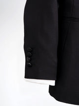 Black men's suit jacket sleeve with four buttons and white cuff detail, formal wear