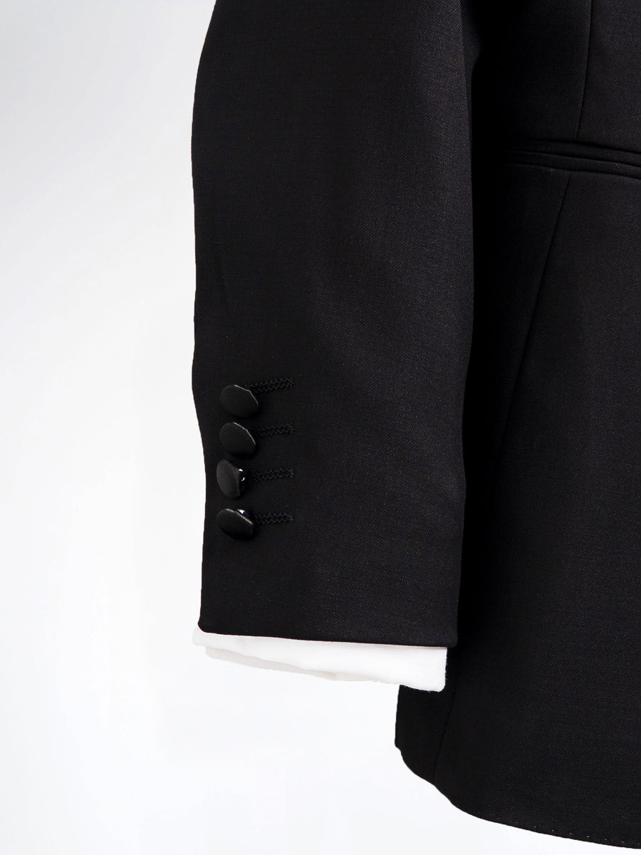 Black men's suit jacket sleeve with four buttons and white cuff detail, formal wear