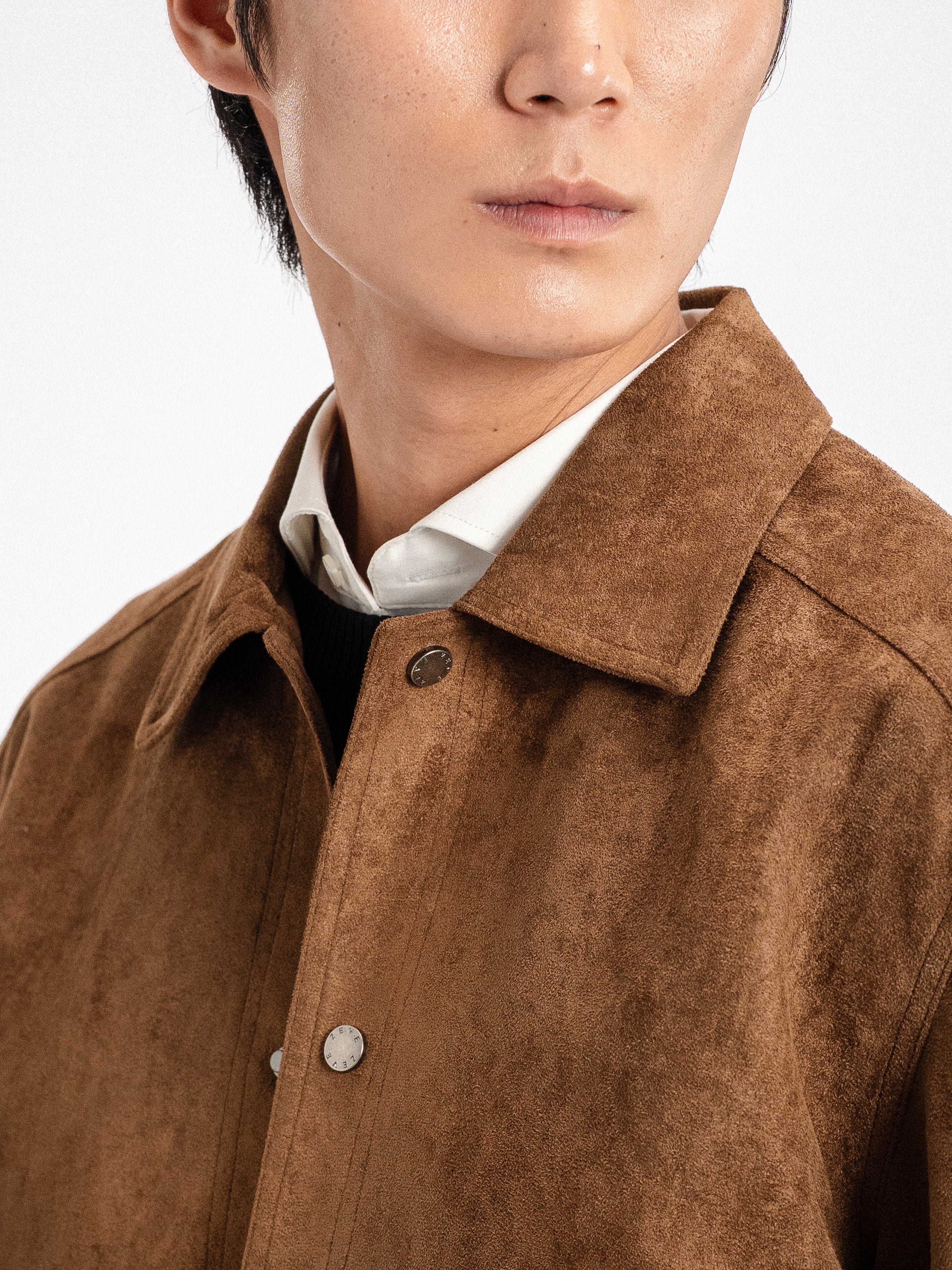 Man wearing brown suede jacket over white shirt, stylish men's apparel