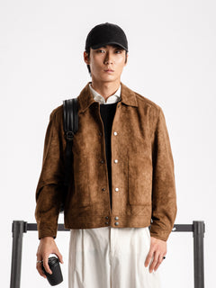 Man wearing brown suede jacket, black cap, and white shirt, holding coffee cup with backpack