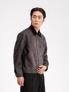 Men's gray suede jacket with black collar, button front, and chest pockets, styled with black trousers