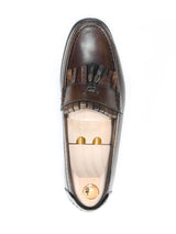 Handmade brown leather fringe loafer with tassels and a wooden shoe tree on white background