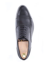 Black leather men’s oxford dress shoe with brogue detail, shown from above on white background