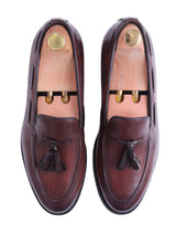 Men's brown leather tassel loafers with wooden shoe trees, formal footwear on white background